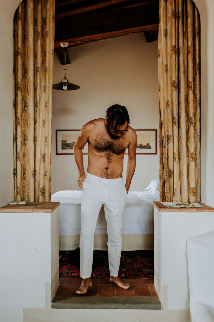French wedding photographer: the groom puts on his white trousers