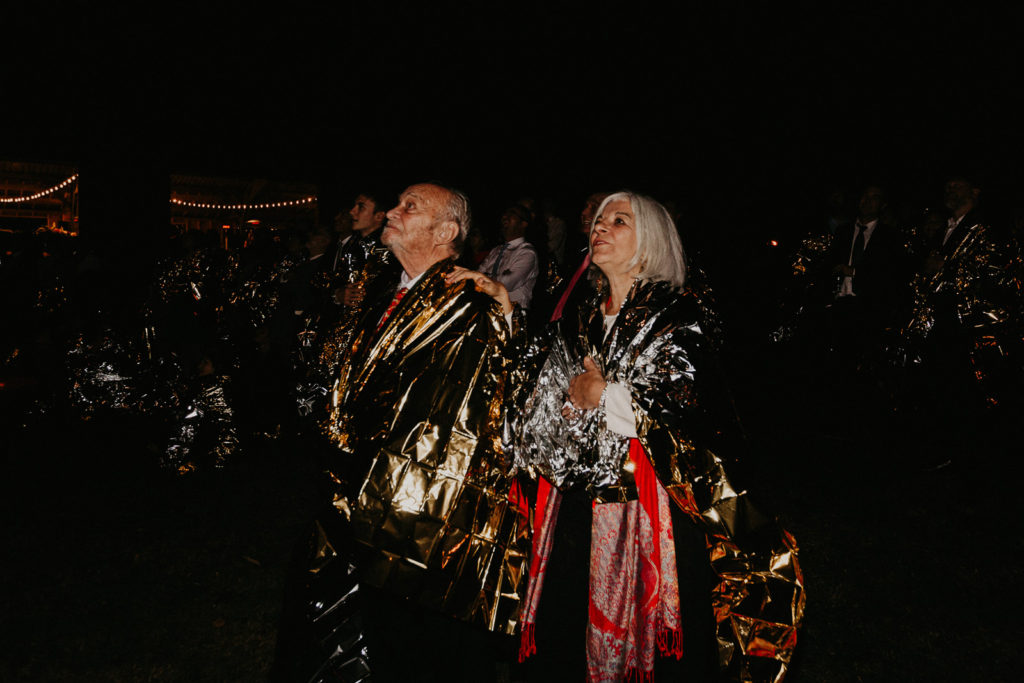 Les invités regardent le feu d'artifice en portant des couvertures de survie